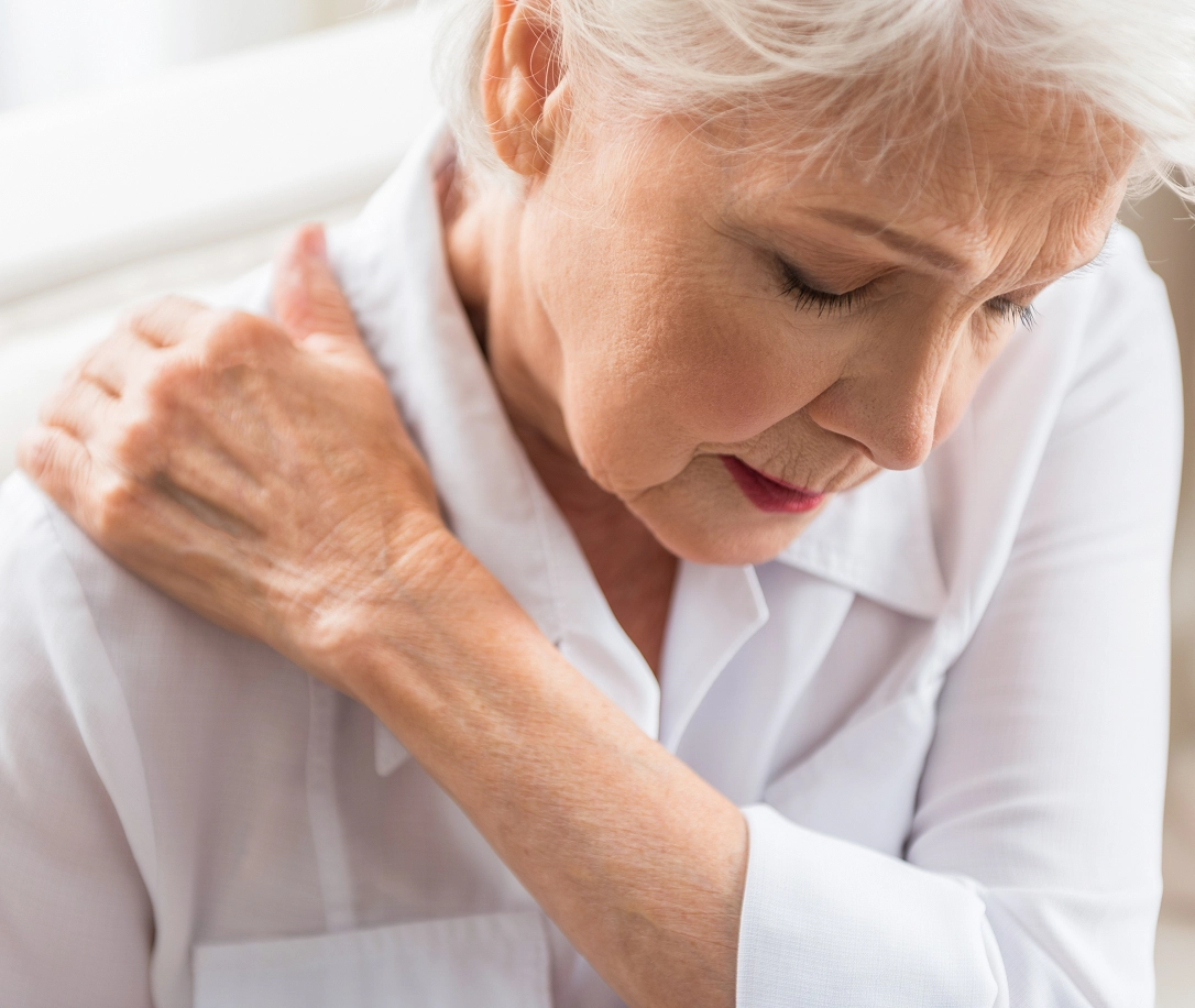 Older woman grabbing her shoulder in pain