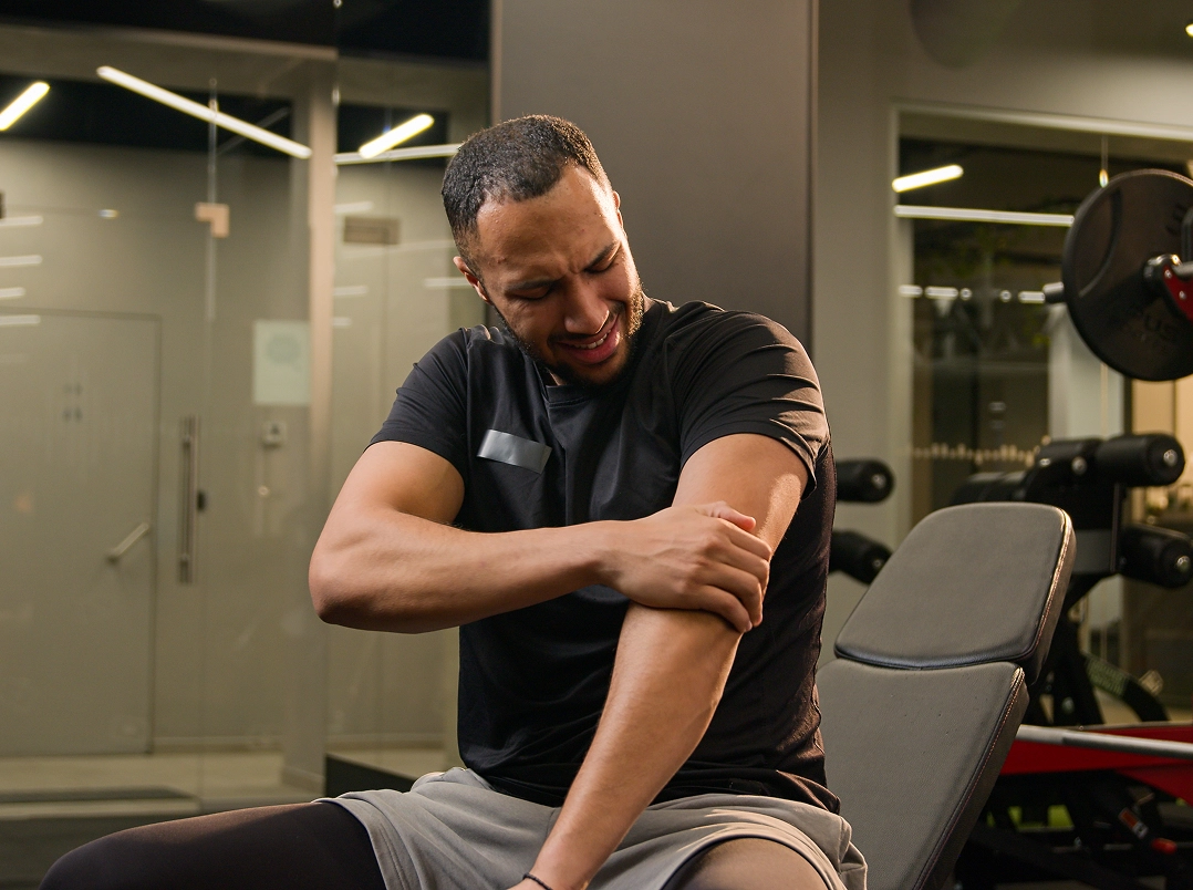 man at gym holding his arm in pain - Sugar Land, TX Orthopaedic Hand, Wrist & Elbow Surgery